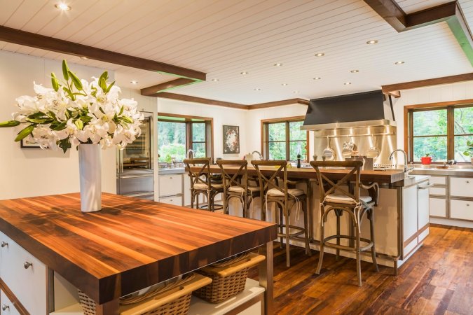 A country style kitchen with an island with butcher block countertops and a breakfast bar with granite countertops.