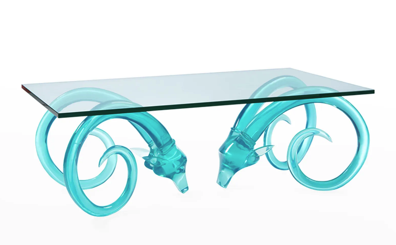 product shot of cocktail table with glass top and base made of two turquoise translucent ram heads with long spiraling delicate horns