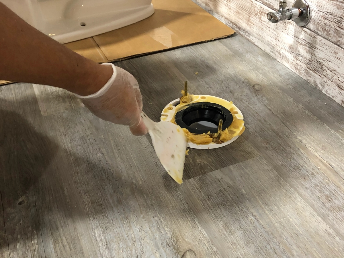 Person scraping old wax ring