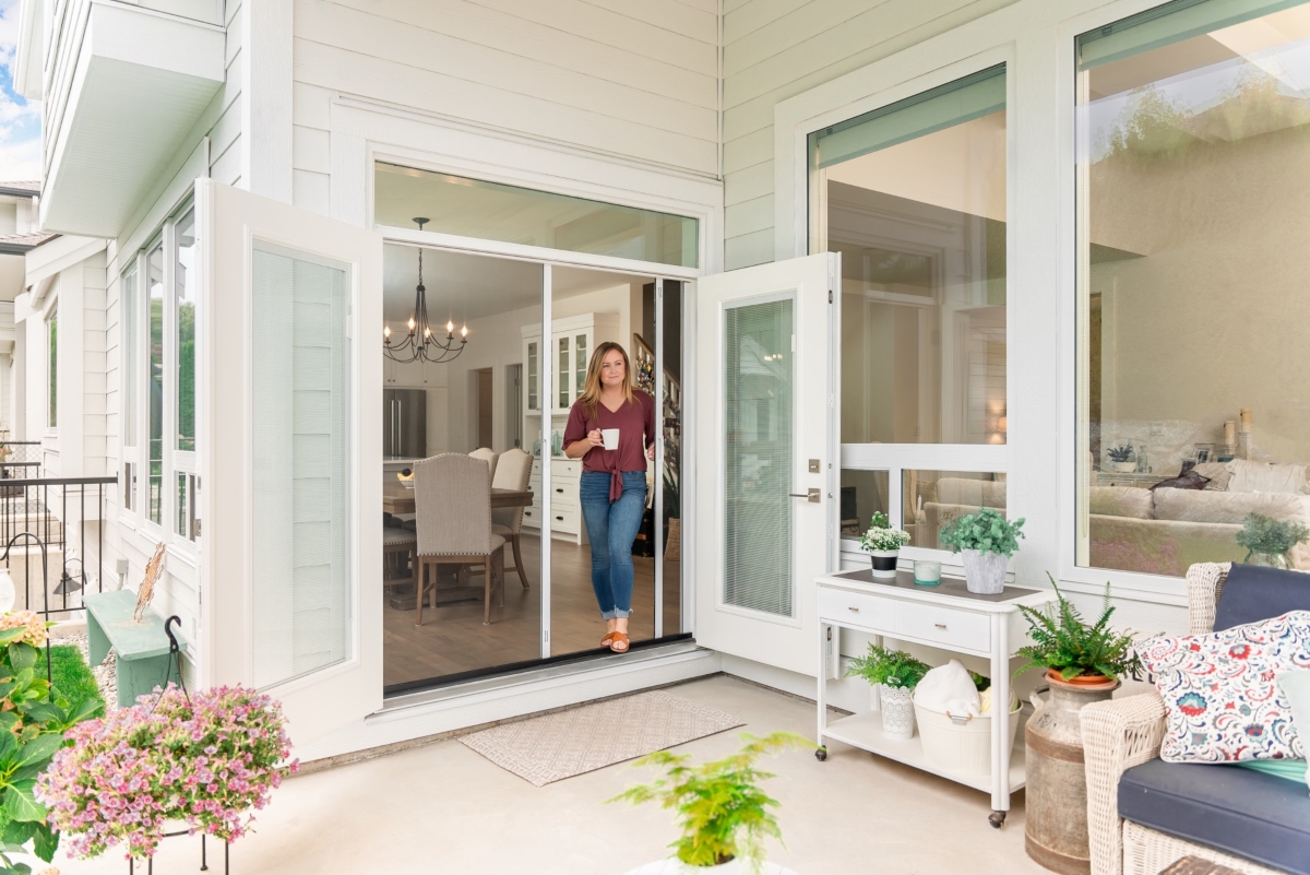 Woman with cup coming outside using screen door