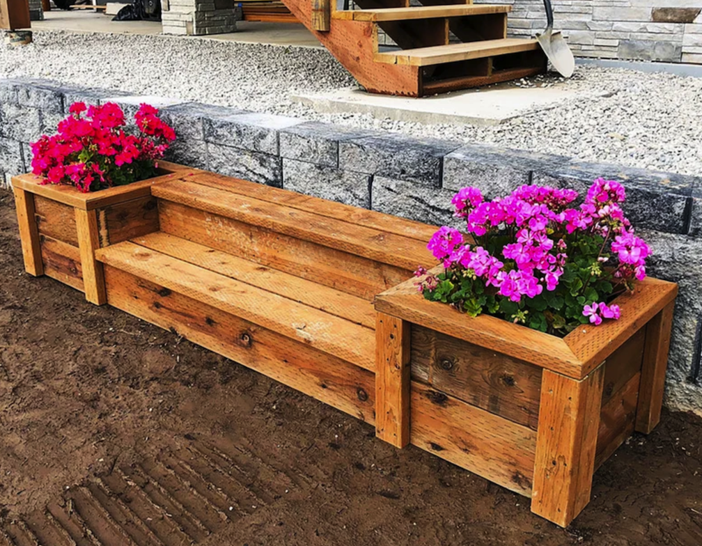wooden bench in backyard landscaping flanked by two built in planter boxes with flowers