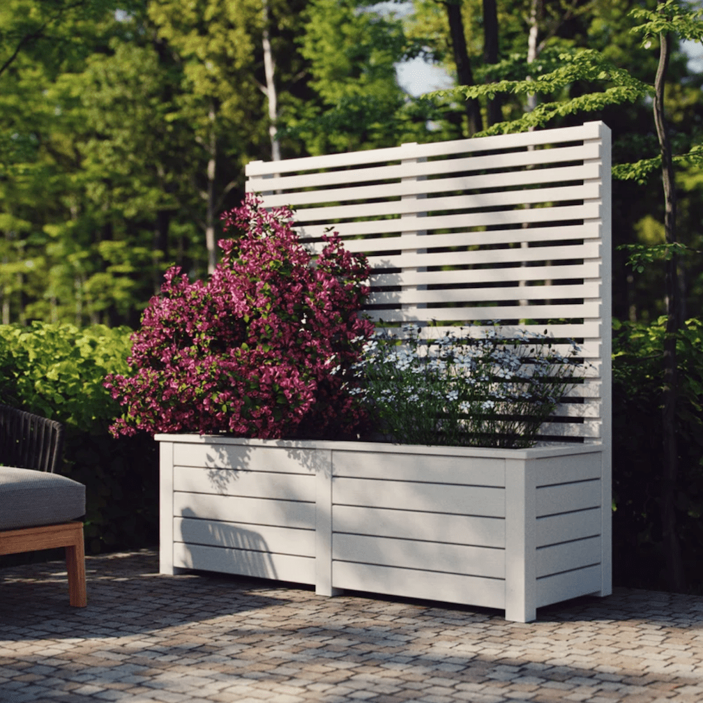 backyard patio in wooded lawn with large wooden rectangular planter box with high slatted screen and filled with beautiful pink flowers