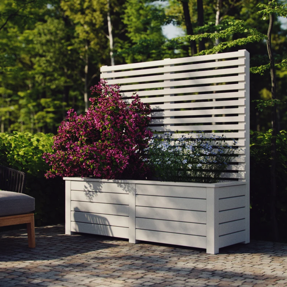 backyard patio in wooded lawn with large wooden rectangular planter box with high slatted screen and filled with beautiful pink flowers