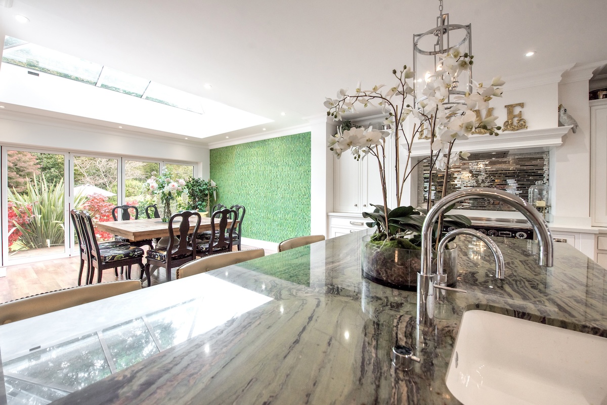A kitchen with a green accent wall and quartzite countertops.