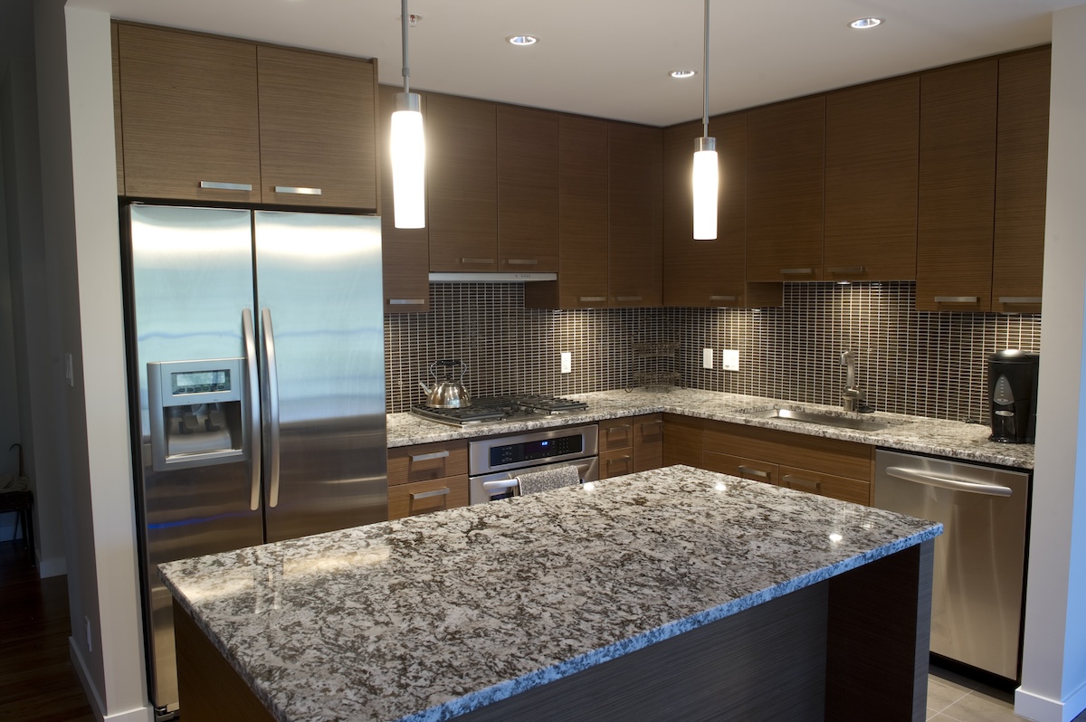 A modern kitchen with wooden cabinetry and solid surface countertops.