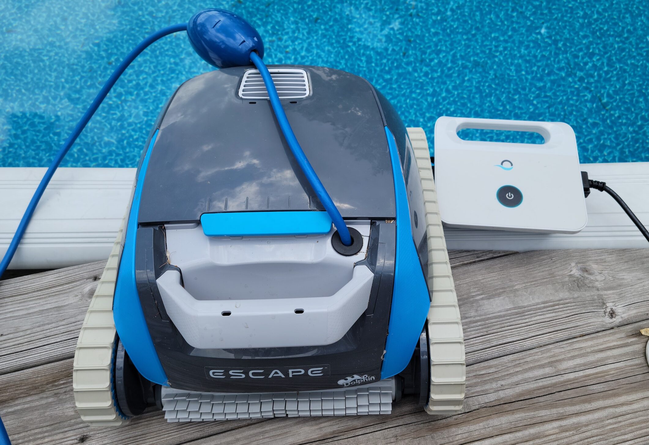 The Dolphin Escape robotic pool cleaner power adaptor set up next to an above-ground pool