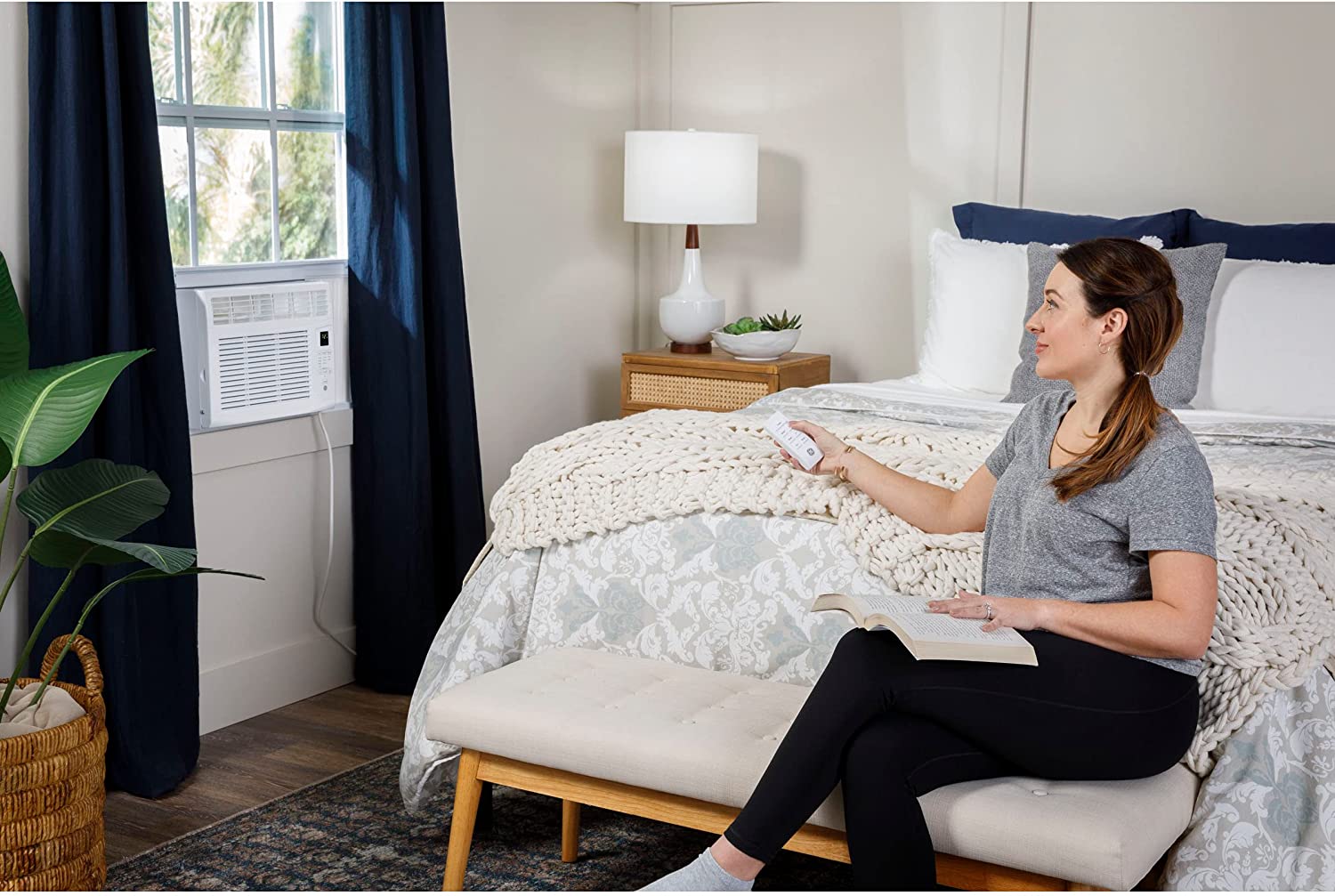 Woman turning on window unit AC with remote control