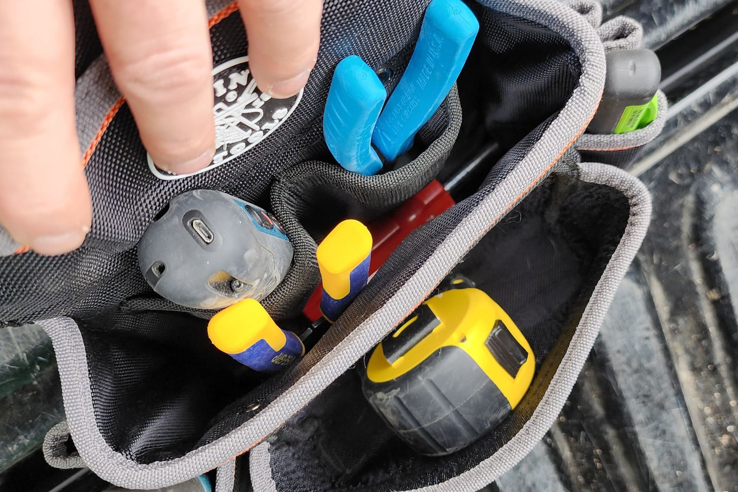 A person reaching for a tool from the Klein Tools Tradesman Pro Electrician's Tool Belt