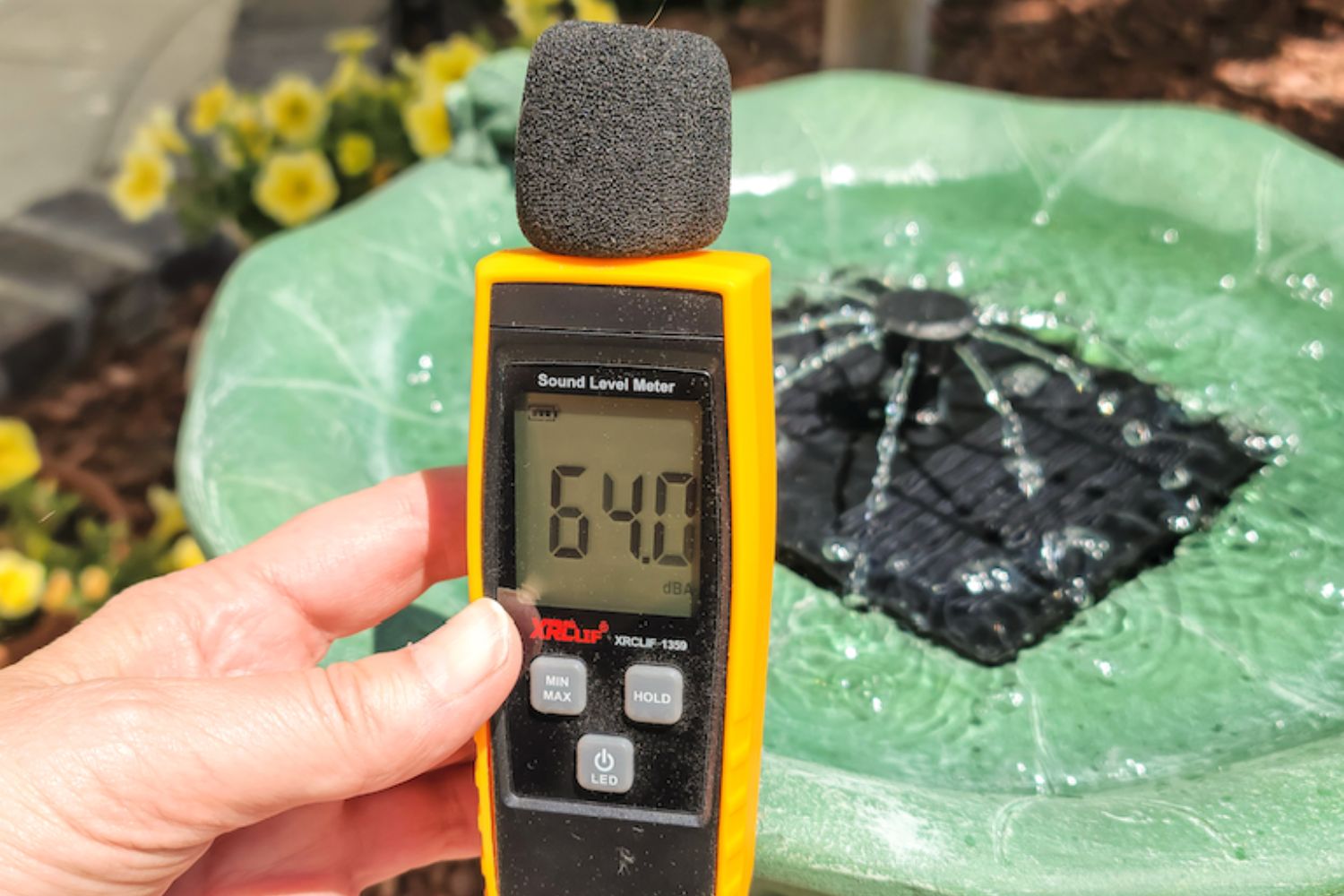 Person measuring decibel level of Smart Solar bird bath fountain