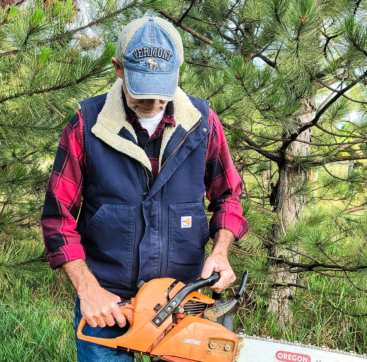A man wearing the Carhartt Flame-Resistant Sherpa-Lined Vest while holding a chainsaw