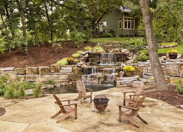 Waterfall built into a hilly backyard with table and chairs set up