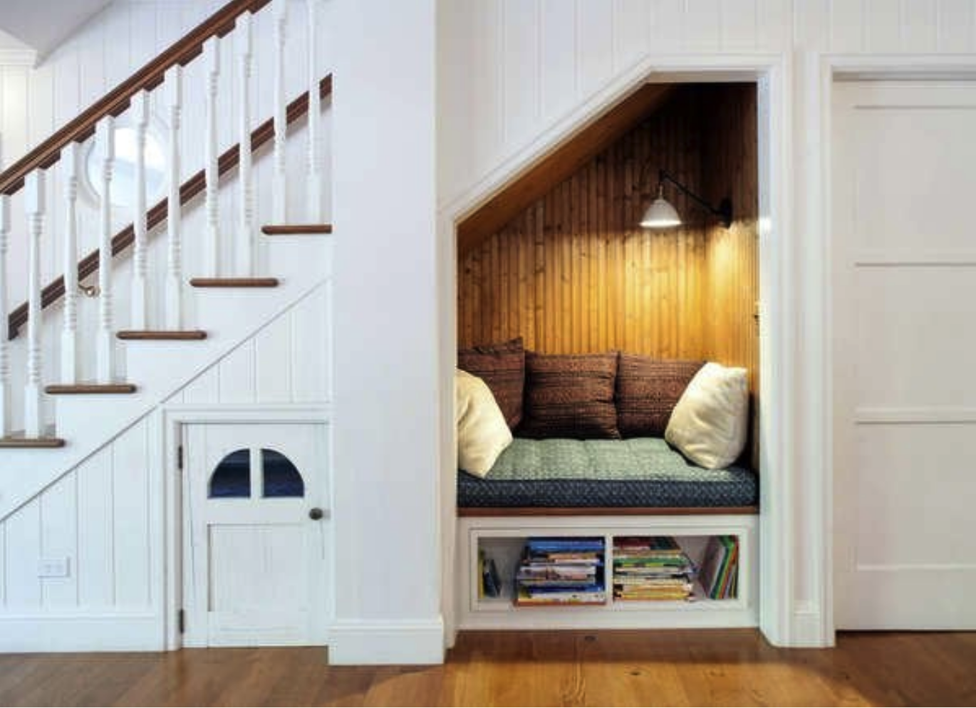 side view of a large white staircase with a nook underneath with cushions and wood paneling