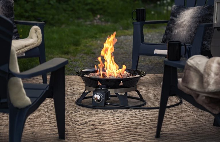 One of the best Fire Pits burning a fire on a patio with two chairs set up next to it
