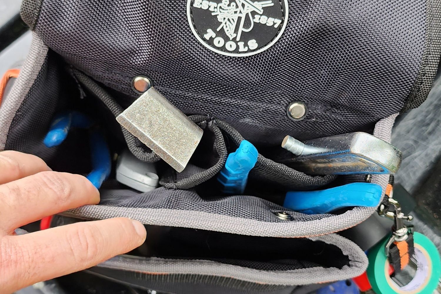 A person reaching for a tool from the Klein Tools Tradesman Pro Electrician&rsquo;s Tool Belt