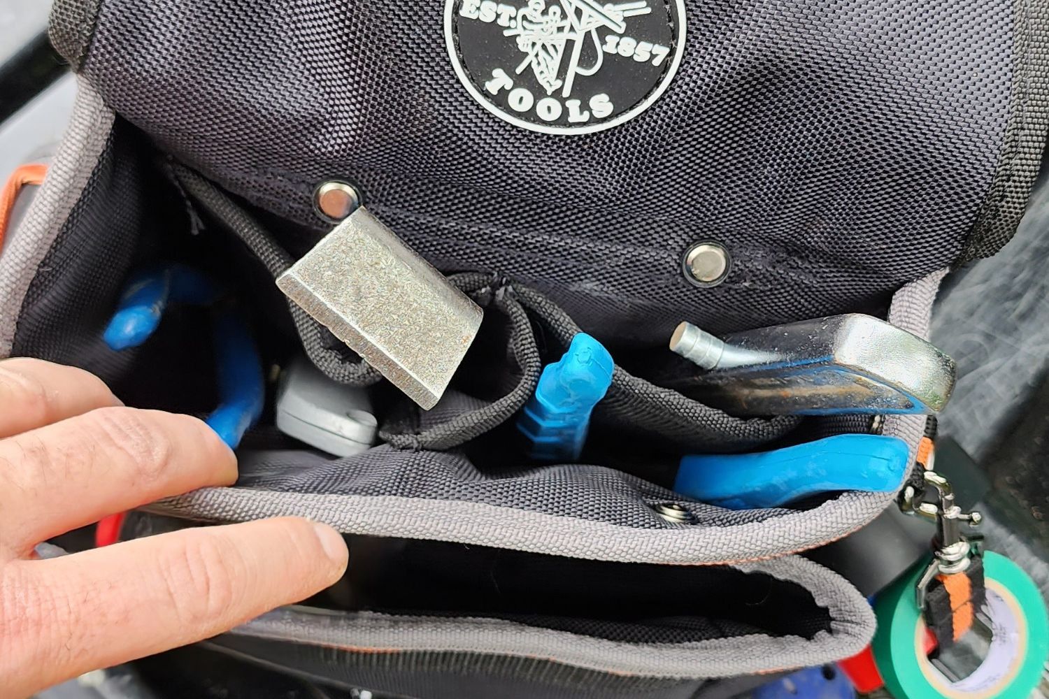 A person reaching for a tool from the Klein Tools Tradesman Pro Electrician's Tool Belt