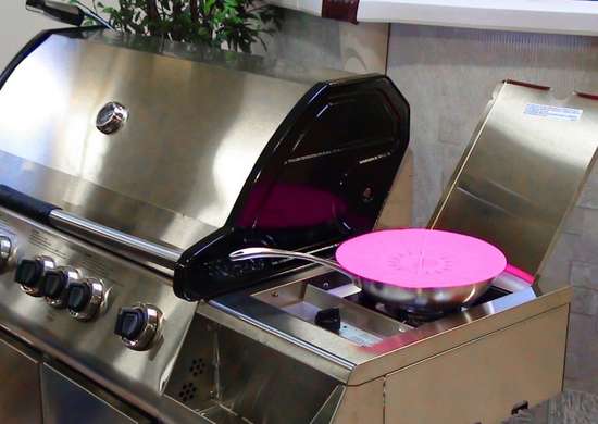 Frying pan covered with pink lid on BBQ burner