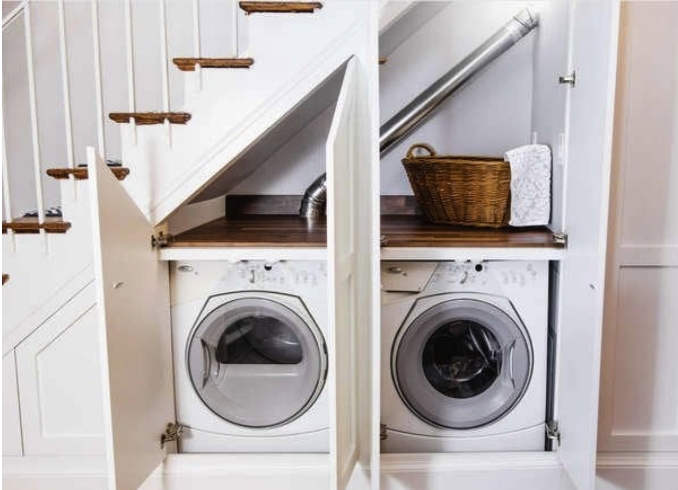 a washer and dryer hidden beneath a staircase in a nook with two open doors