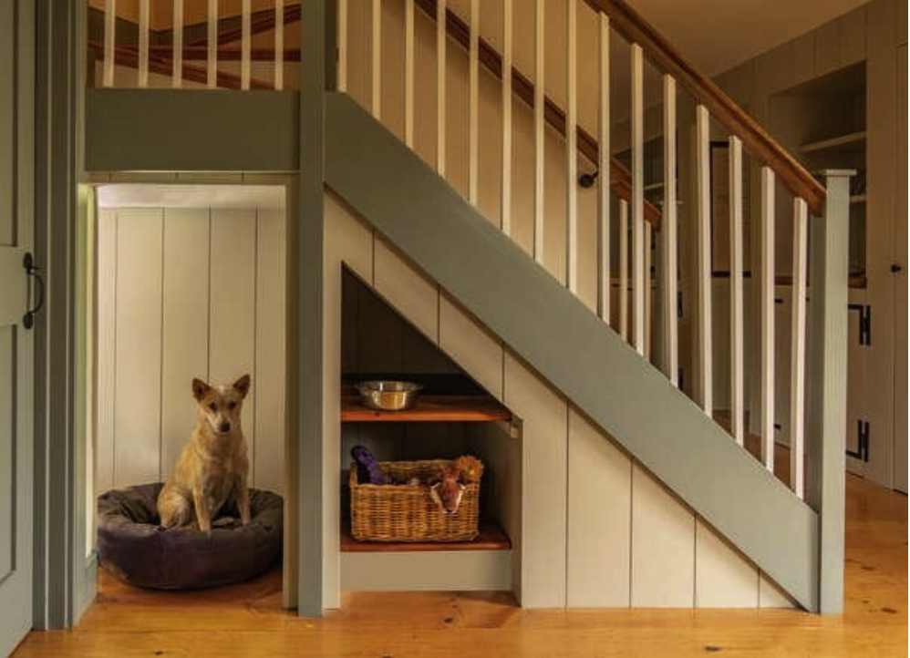 staircase with green siding with nook for a dog who sits on a dog bed and a shelf with dog toys