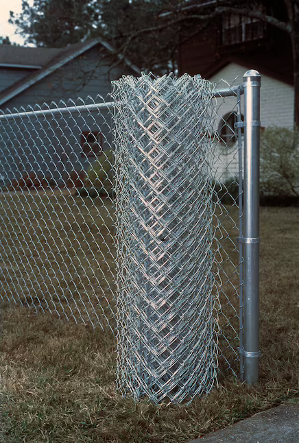 chain link fence installed in home yard with roll of fencing in front