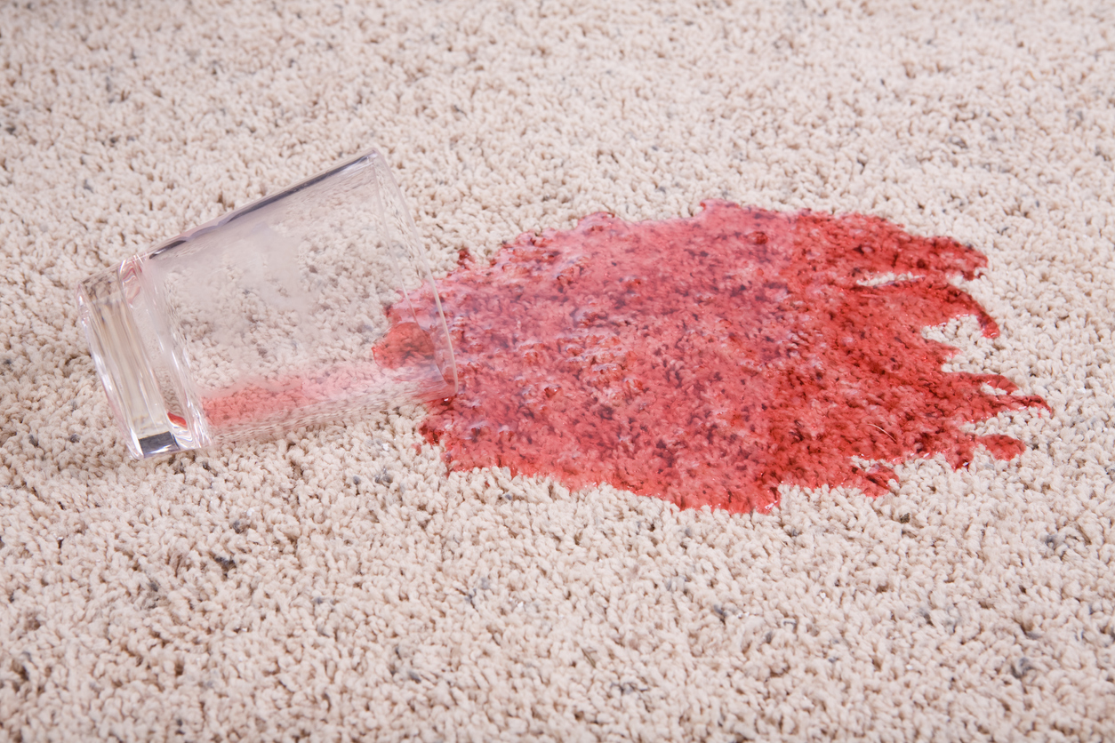 light colored carpet with glass spilling red liquid