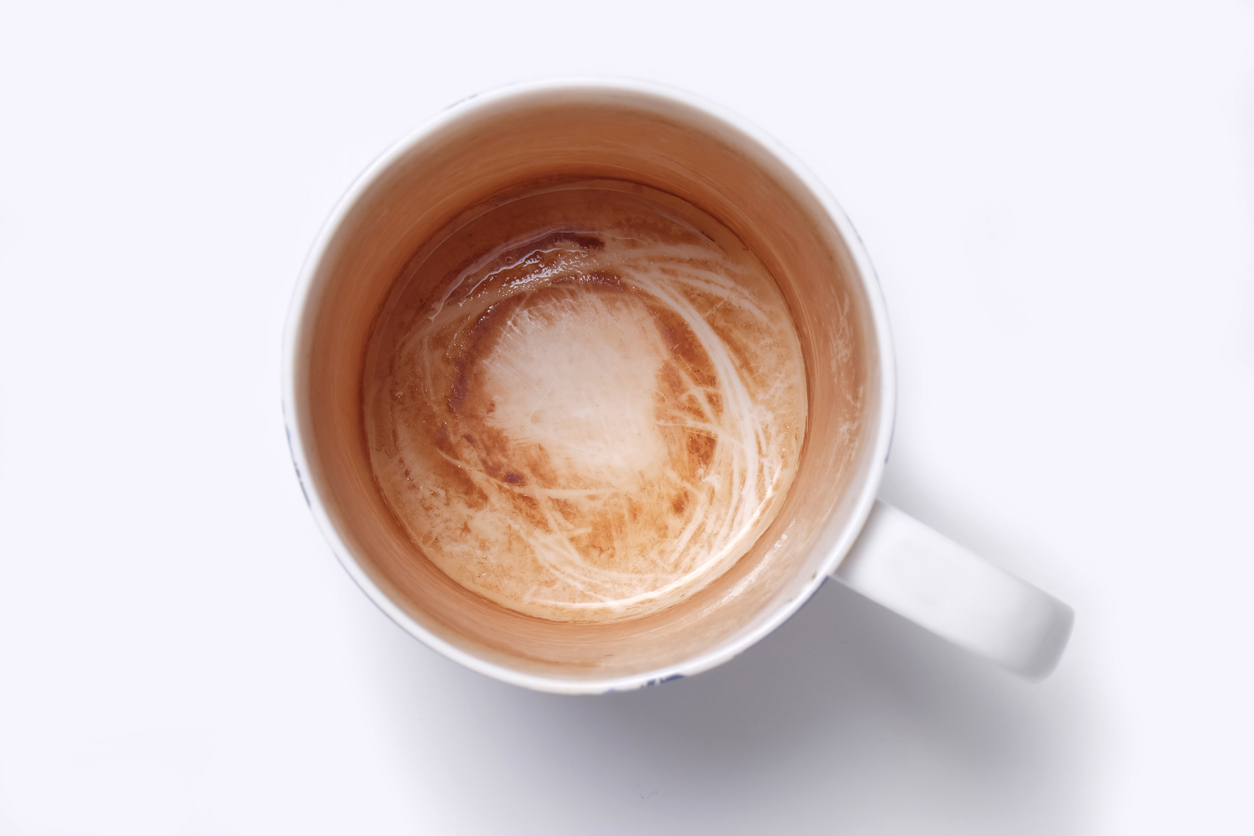 overhead view of mug with coffee stains against white background