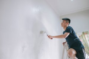 An asian teenage boy painting his bedroom, apartment renovation during sunset