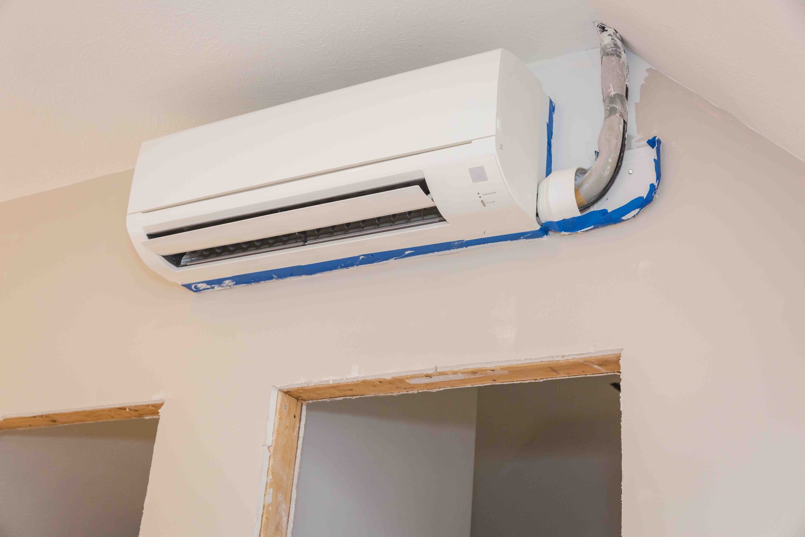 Mini-split ductless air conditioning unit installed in unfinished room with painter's tape around it