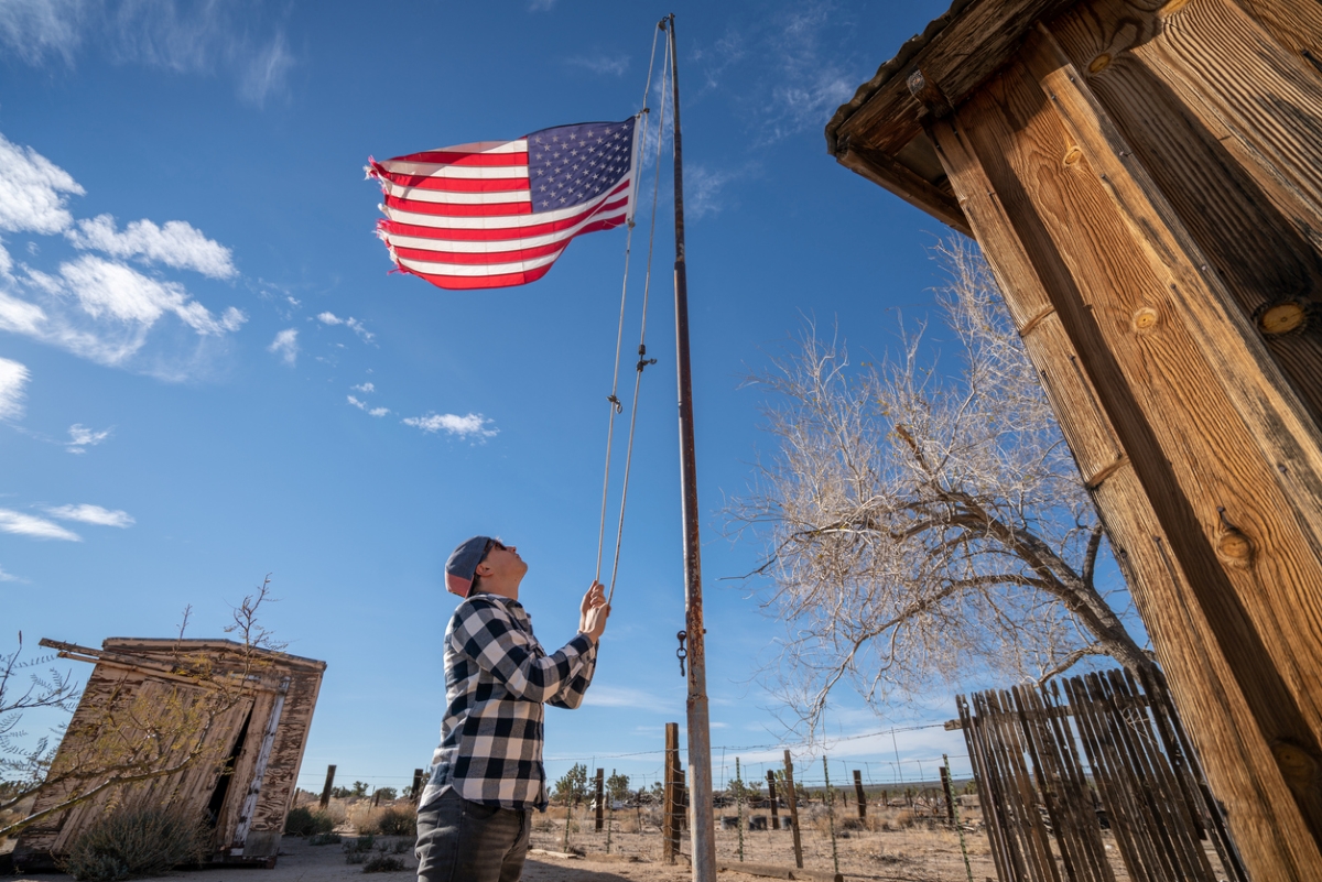 Young man hoisting American flag up flagpole