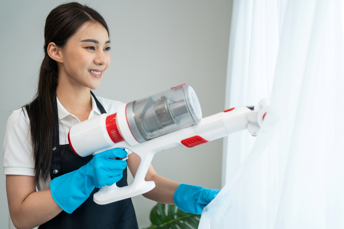 Woman using vacuum on curtains