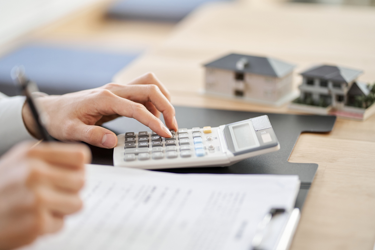 man's hands at desk using calculator with loan contract on desk