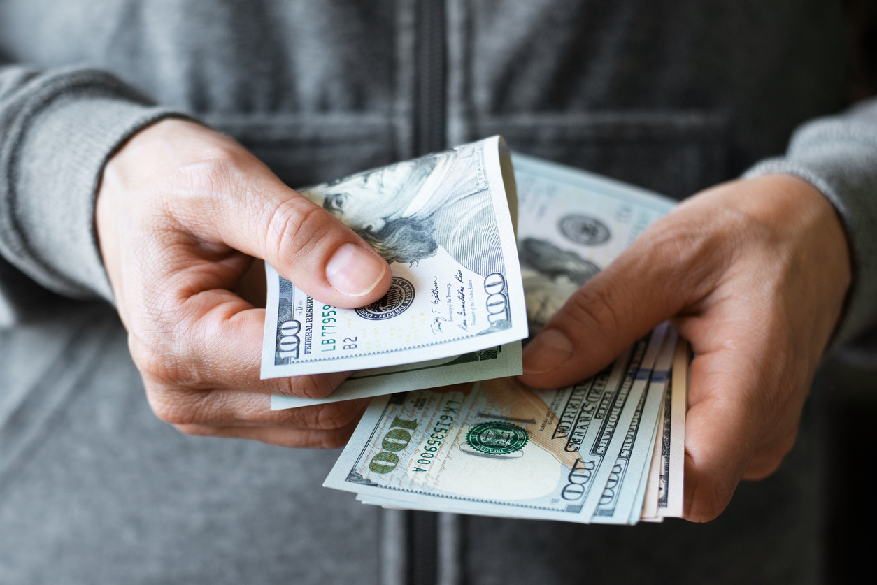 man in grey sweatshirt holding cash in hands