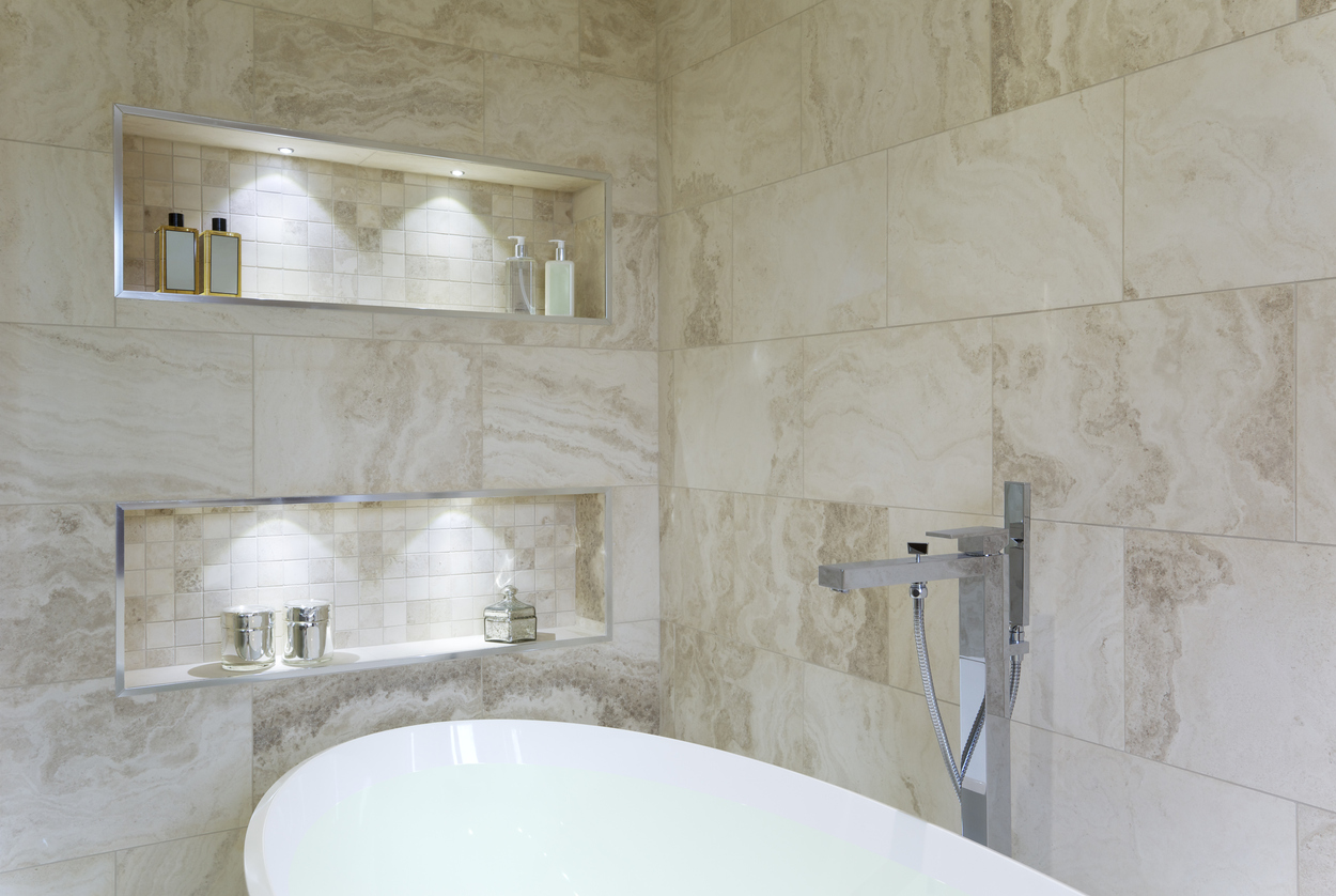marble bathroom with white tub with two stacked niches above tub containing lights