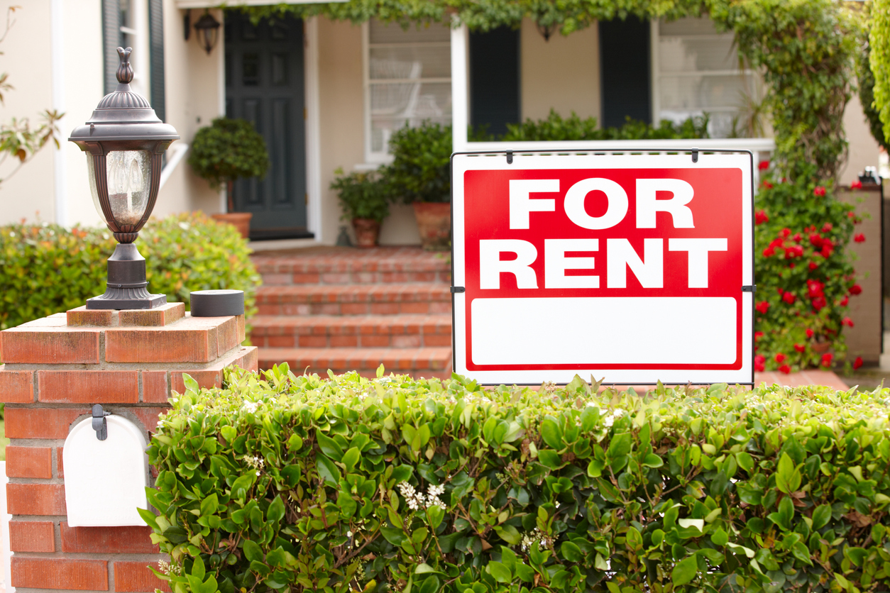 red for rent sign on front porch of stately home with shrubs and red flowers