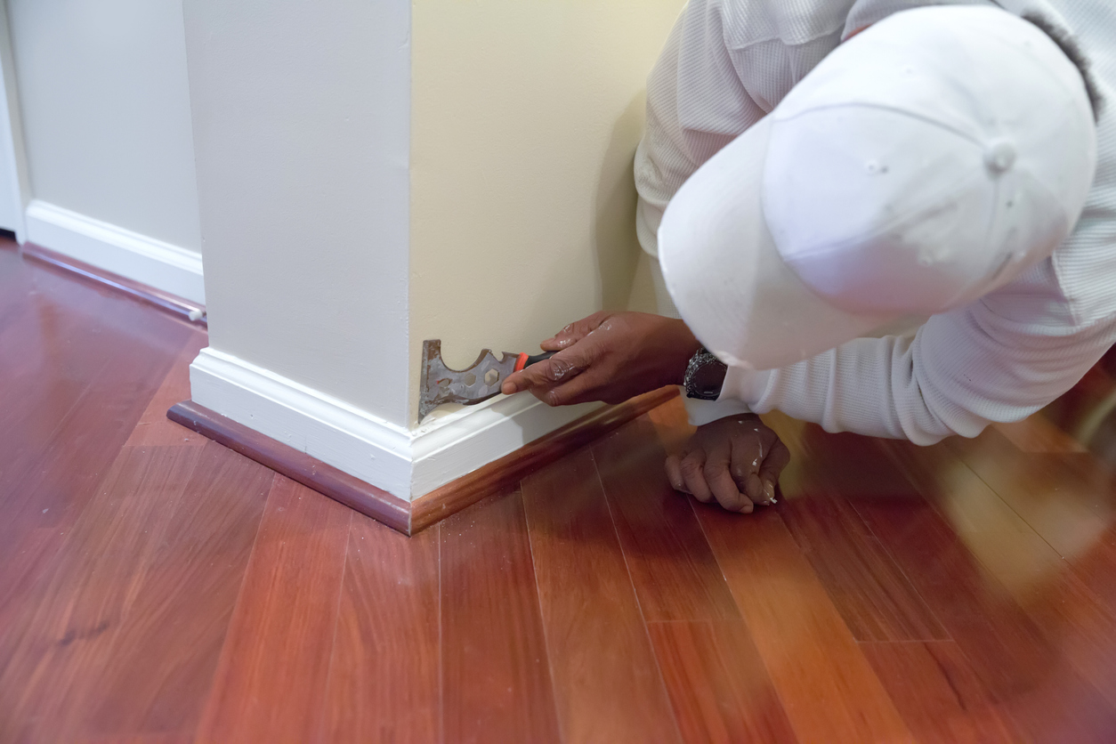 Painter uses tool on a baseboard