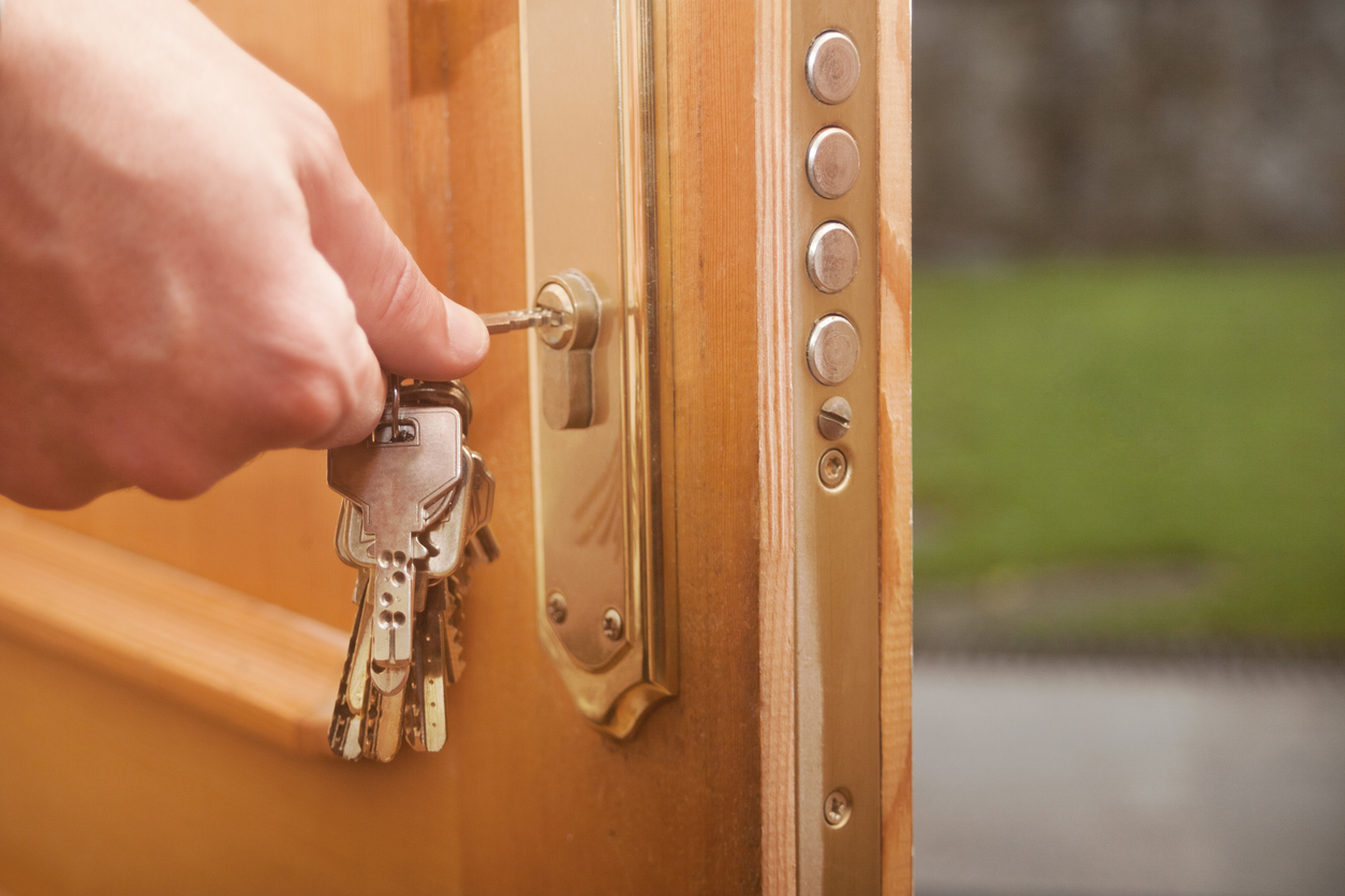 hand putting key in lock of wooden door to lock it