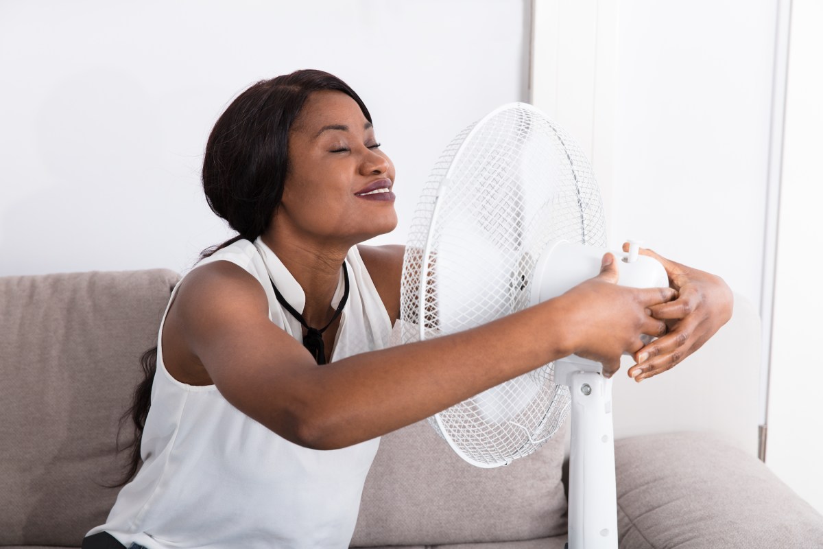 woman-leaning-forward-and-hugging-a-fan-to-stay-cool