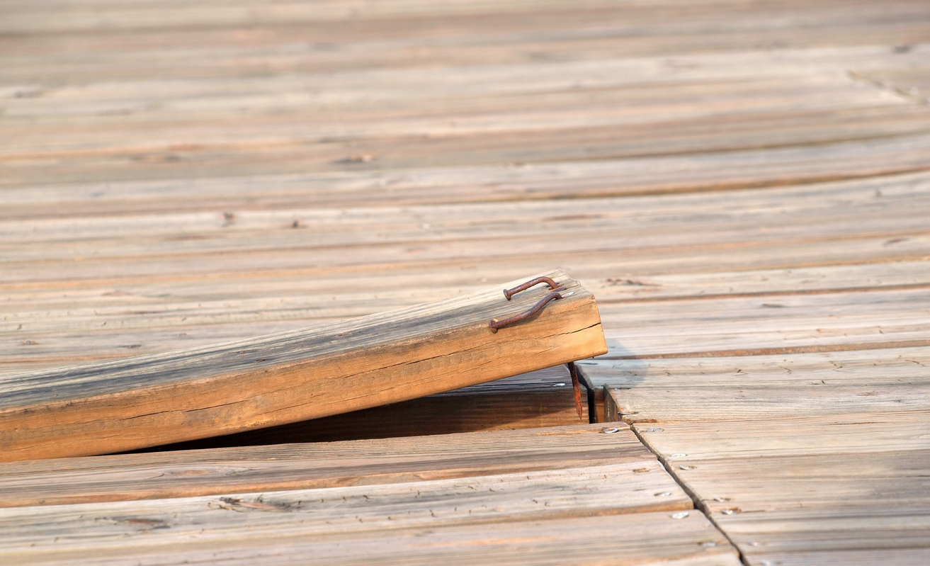 a-loose-wooden-board-with-rusty-nails-sticks-up-from-a-deck