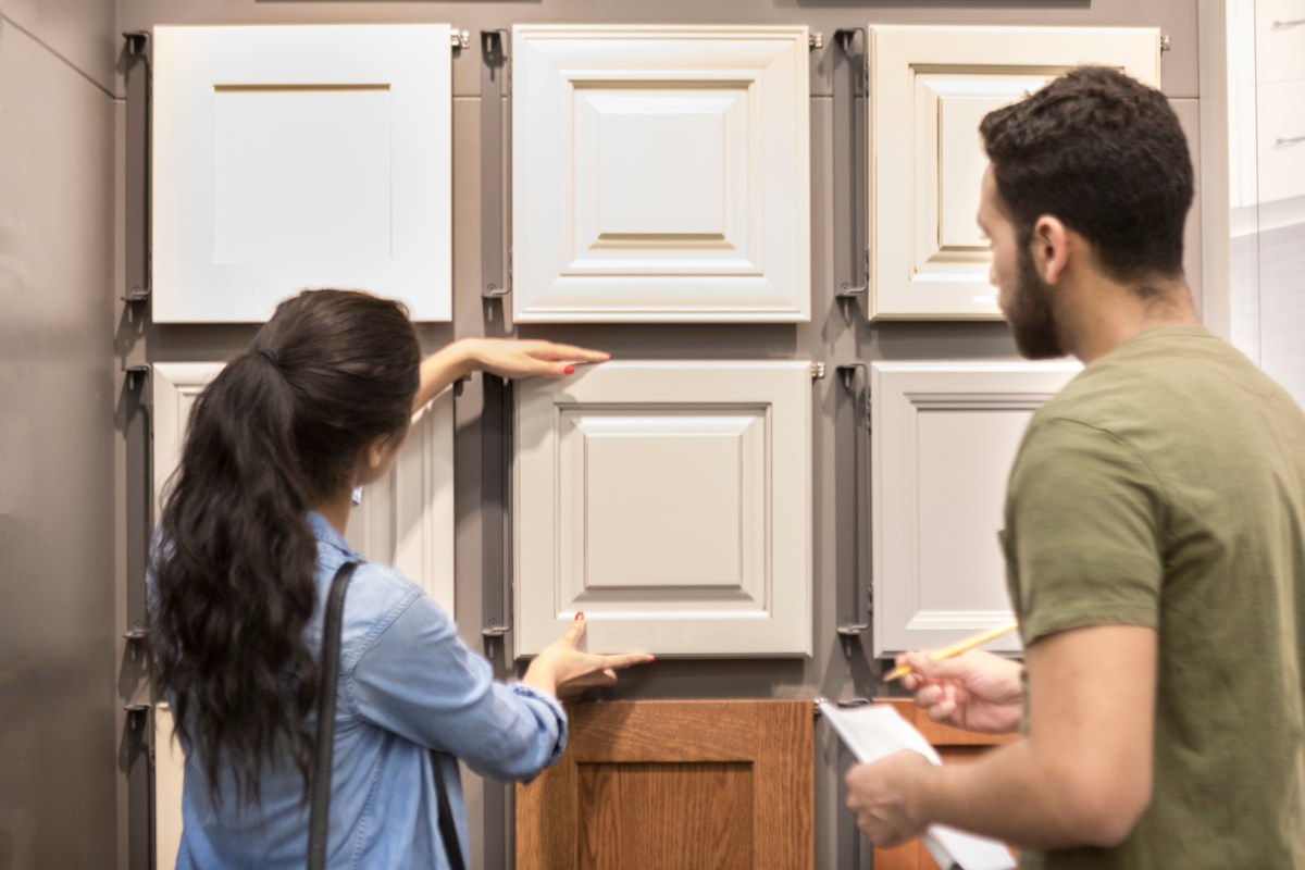 Young woman looks a cabinetry display in home improvement store. A male salesperson is helping her.