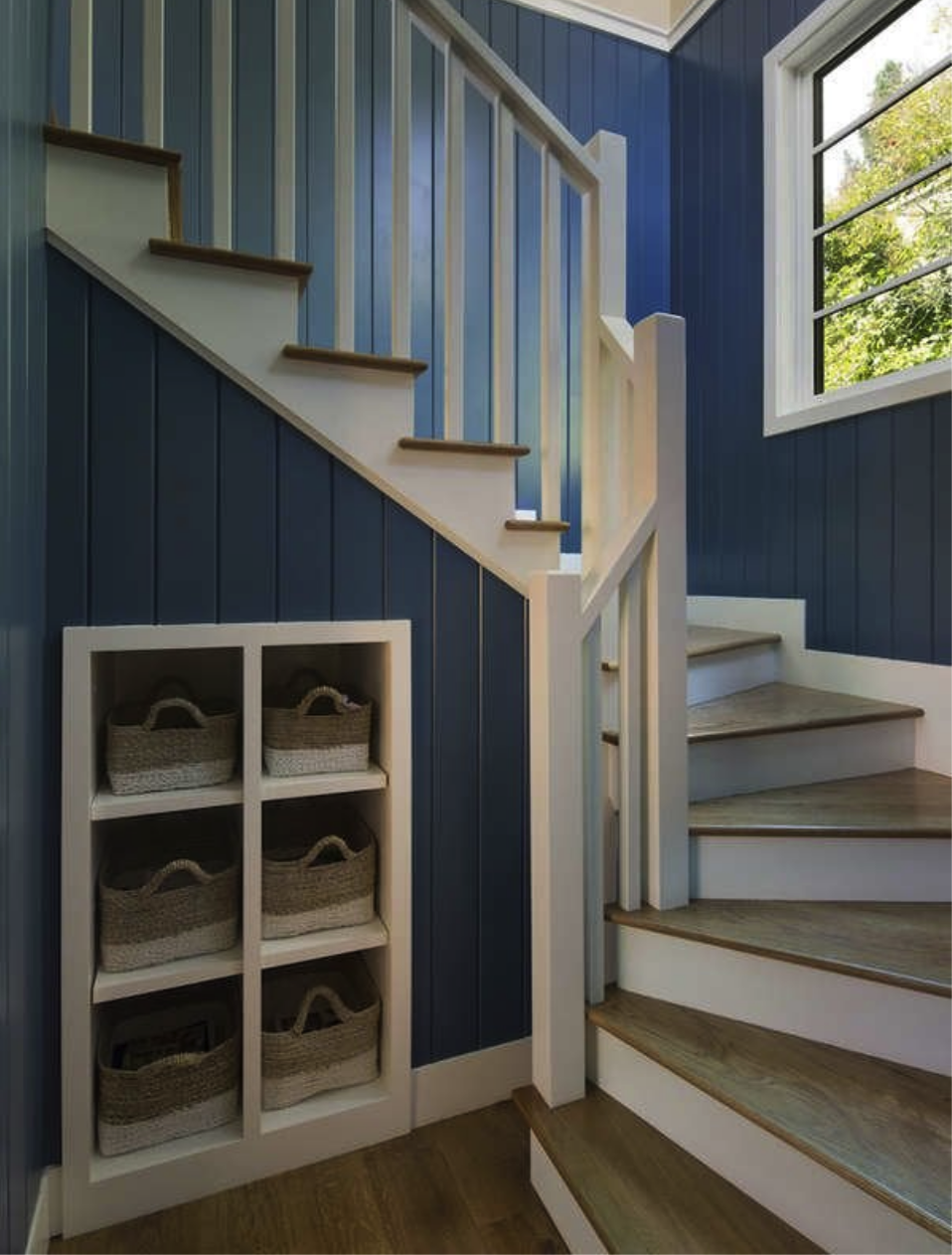 winding staircase with blue walls and small cubby holes in wall with baskets for storage