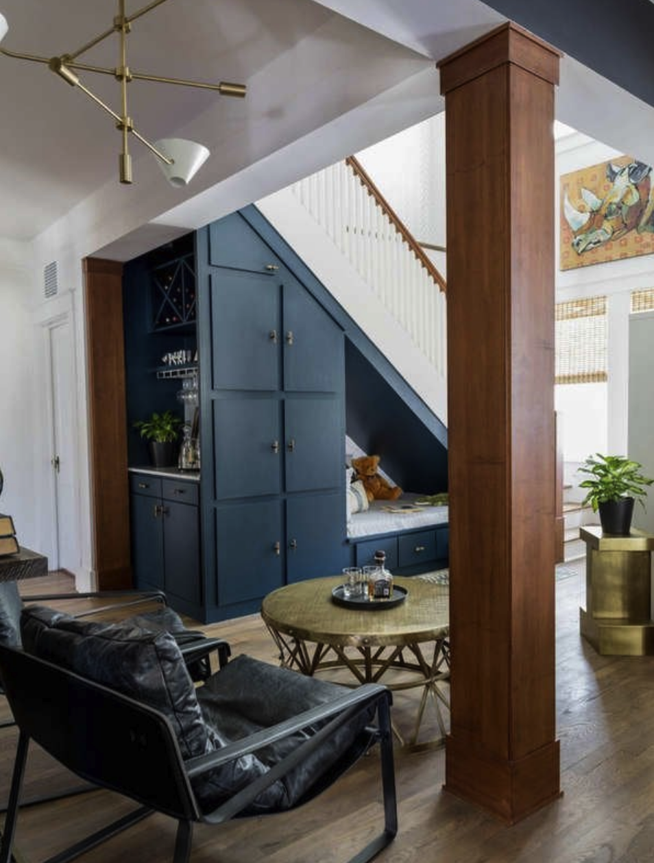 spacious living room with tall blue cabinets and storage nook under staircase with mini bar