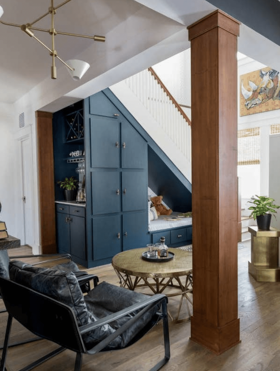 spacious living room with tall blue cabinets and storage nook under staircase with mini bar
