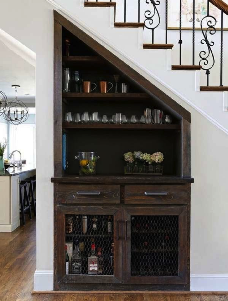 view of dark wood cabinet and mini bar underneath elegant staircase in open plan living room