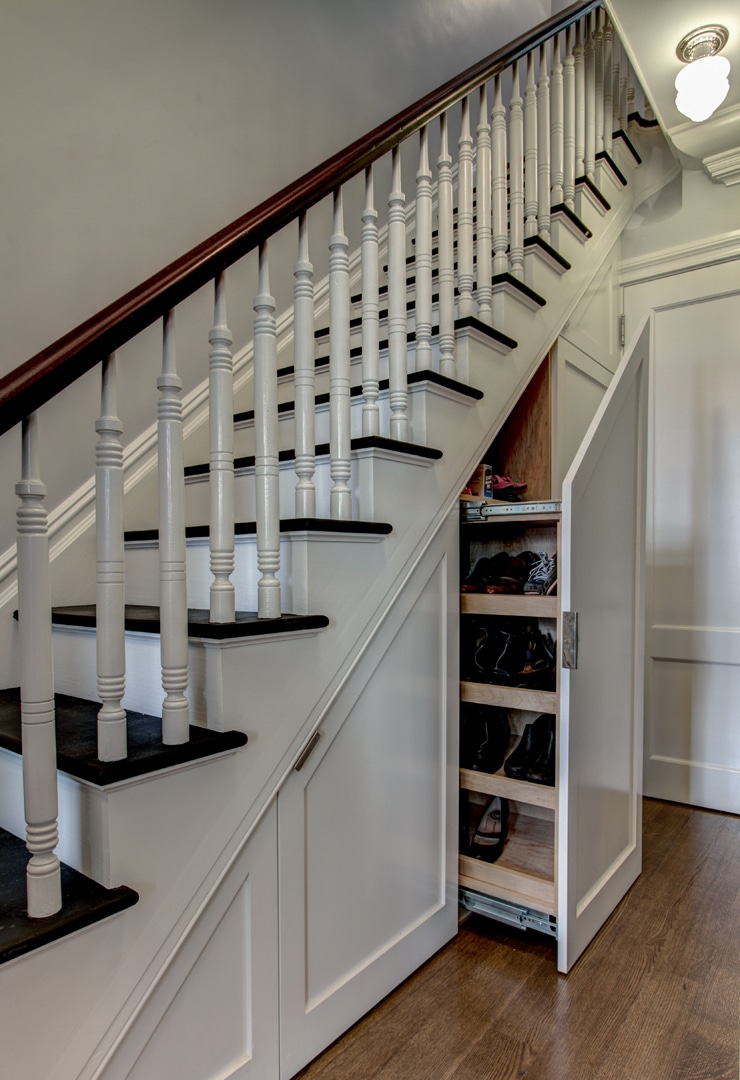 tall white staircase in front hall with a large tiered drawer opened out underneath