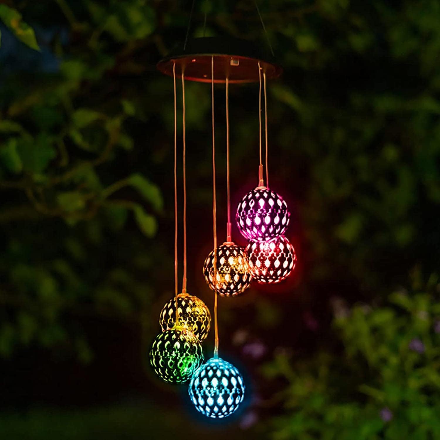 Solar powered multicolored wind chimes hanging from tree
