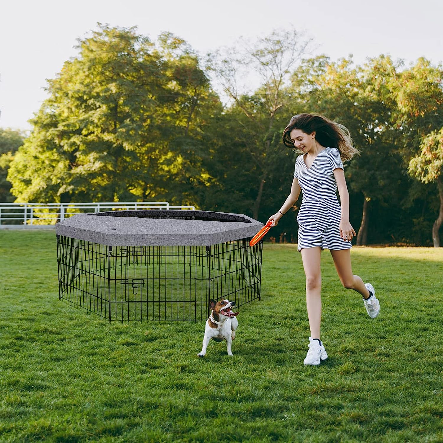 Woman playing with dog with covered dog pen in the background