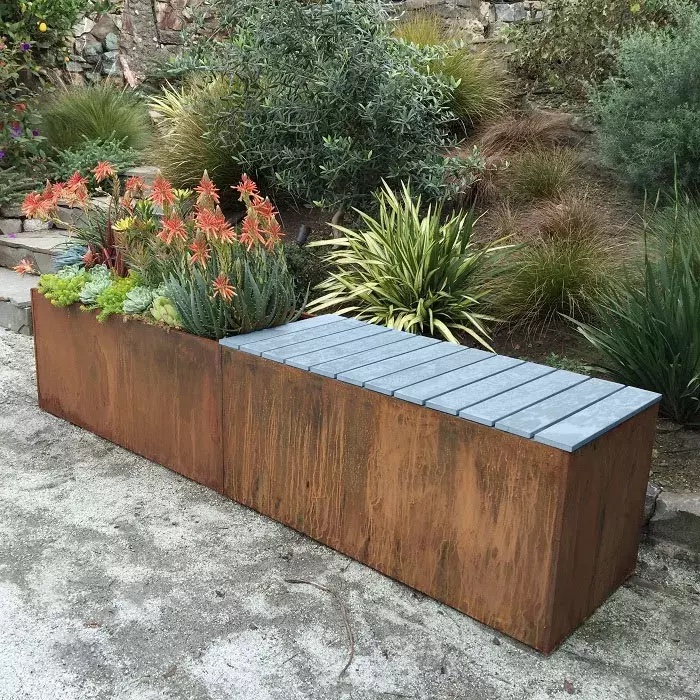 A wooden garden bench that has a built-in planter box with colorful plants.