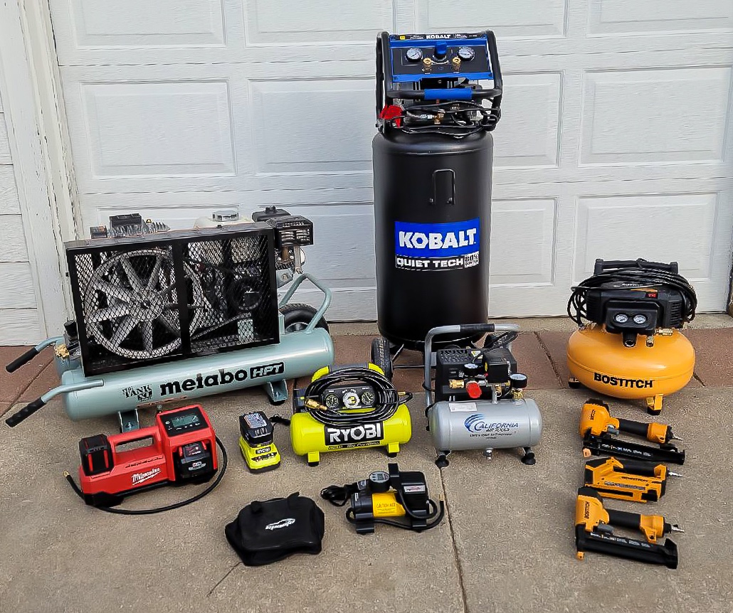 A group of the best home air compressors in front of a garage door before testing.