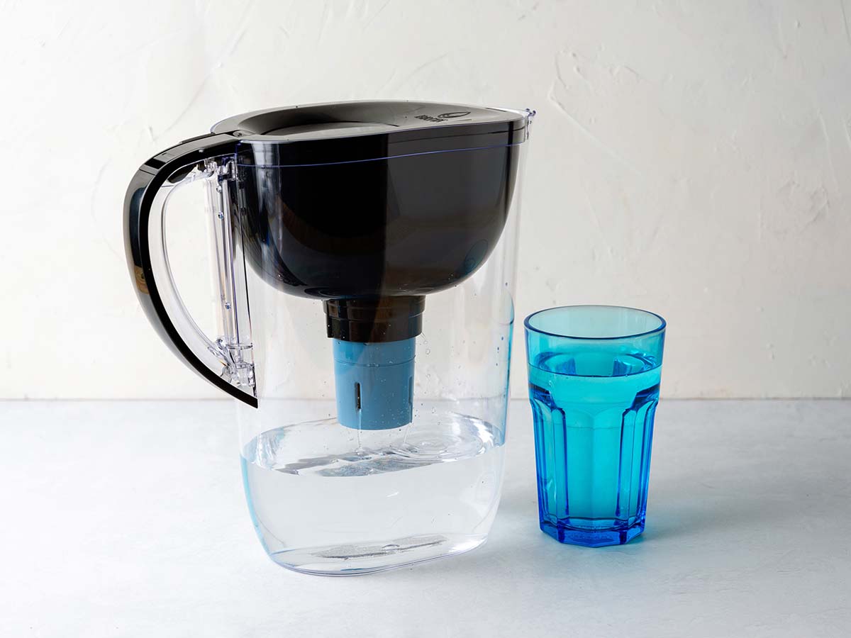 Brita Tahoe Water Filter Pitcher filled with water next to blue cup