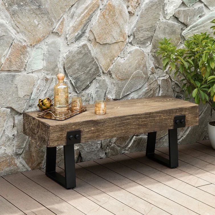 Industrial-style garden bench in front of a stone wall.