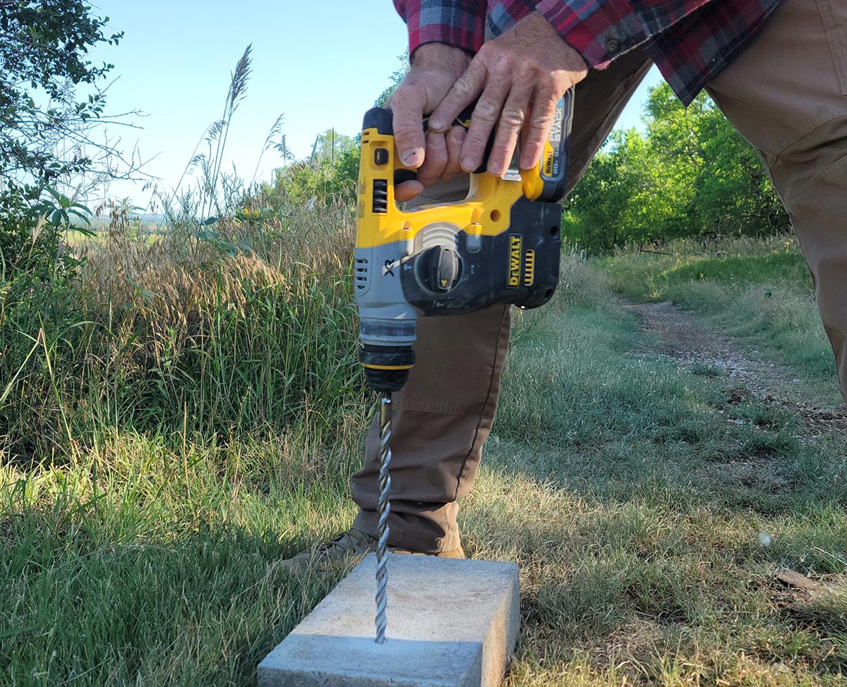 A person using a DeWalt concrete drill powered by a DeWalt PowerStack battery